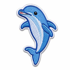 Peut inclure: Un écusson brodé représentant un dauphin de dessin animé dans des tons bleu et blanc. Le dauphin est représenté dans une pose bondissante avec un ventre blanc, un petit œil noir et une bouche rose. Le motif est entouré d'une bordure blanche.