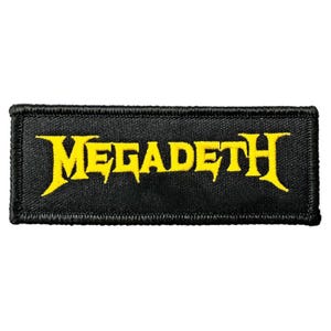 May include: A rectangular embroidered patch with a black background and a yellow border. The text MEGADETH is stitched in a bold, stylised yellow font across the centre of the patch, featuring sharp, angular lettering characteristic of the logo.