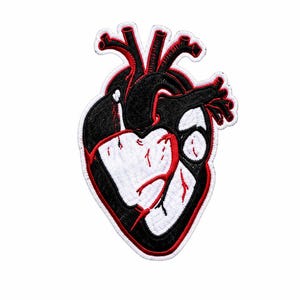 May include: An embroidered patch in the shape of an anatomical human heart. The design features a black and white colour scheme with bold red outlines and red vein details. The patch has a white border and a textured, stitched surface finish.