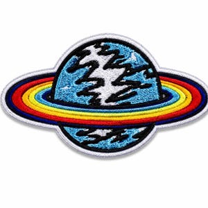 May include: An embroidered patch featuring a circular planet design with a light blue surface and jagged black markings. The planet is encircled by a vibrant ring consisting of concentric bands in red, orange, yellow, and blue, finished with a white border.
