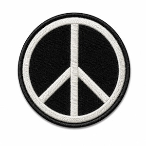 Puede incluir: Un parche bordado circular que presenta un fondo negro con un diseño de símbolo de la paz en blanco. El emblema consiste en un borde circular blanco que encierra una línea vertical y dos líneas diagonales que se unen en el centro.