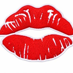 Könnte beinhalten: Ein roter Stickaufnäher in Form von Lippen. Das Design besteht aus leuchtend rotem Garn, das die Lippenform bildet, mit weißen Garnakzenten für Highlights und Textur, alles umrandet von einer dicken weißen Bordüre für einen sauberen Abschluss.