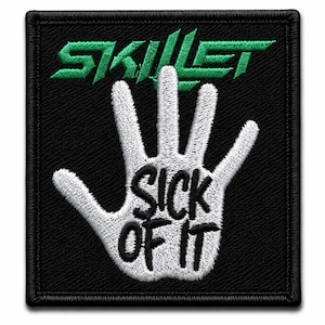 Op de afbeelding: Een vierkante geborduurde patch met een zwarte achtergrond. Het bevat de groene tekst SKILLET bovenaan en een witte handafdruk in het midden. De woorden SICK OF IT zijn in het zwart geborduurd over de palm van de witte handafdruk.