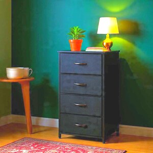May include: A black four-drawer storage chest with a metal frame and fabric drawer fronts. Each drawer features a curved handle. The chest stands upright on a wooden floor, providing a vertical storage solution for organizing various household items.