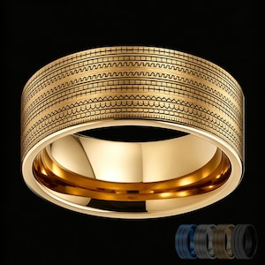 May include: A wide gold-toned band ring featuring a series of horizontal engraved patterns, including straight lines, zigzags, and semi-circular arches. The interior of the ring is smooth and polished. Four additional color variations are shown below.