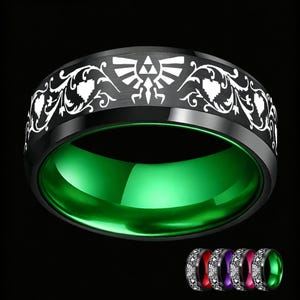 Puede incluir: Un anillo de banda negra con un símbolo de Trifuerza grabado en blanco y complejos motivos florales en la superficie exterior. El interior del anillo es de un verde vibrante y pulido. En la esquina inferior derecha se muestran versiones más pequeñas con interiores en rojo, morado, rosa y verde.