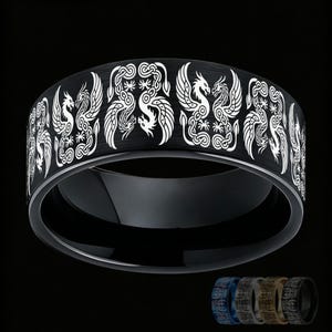 Puede incluir: Un anillo negro con un patrón grabado en blanco que se repite, mostrando dos dragones enfrentados con detalles de nudos intrincados. La banda tiene un acabado liso y pulido con un perfil ancho. Se muestran versiones más pequeñas en azul, plata, oro y negro.