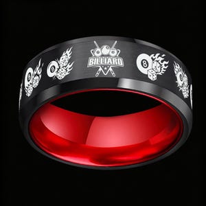 May include: A black band ring with a brushed finish and a vibrant red interior. The exterior features a repeating white laser-engraved pattern of billiard balls, dice, and flames, along with a central logo reading BILLIARD with crossed cues.
