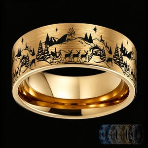 Puede incluir: Un anillo de tono dorado con acabado cepillado que presenta un paisaje invernal grabado con láser en negro. El diseño muestra una escena nevada con pinos, una pequeña cabaña y un trineo tirado por renos bajo un cielo estrellado.