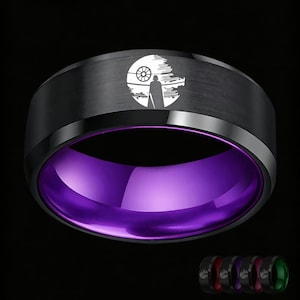 Könnte beinhalten: Ein schwarzer Bandring mit gebürsteter Oberfläche außen und einem leuchtend violetten Innenbereich. Die Außenseite zeigt eine weiße, lasergravierte Grafik einer Silhouette, die vor einer großen, kreisförmigen Raumstation steht.