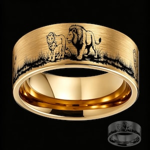 Könnte beinhalten: Ein goldfarbener Ring mit gebürsteter Oberfläche und einer schwarzen Lasergravur, die ein Löwenrudel im hohen Gras zeigt. Das Band hat eine polierte Innenseite und ein breites, flaches Profil. Eine kleinere Ansicht des Rings ist unten zu sehen.