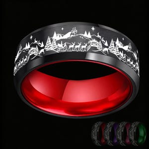 Puede incluir: Un anillo negro con un grabado láser blanco de un paisaje invernal con renos, un trineo y pinos en la banda exterior. El interior del anillo es de un color rojo vibrante y pulido. Se muestran cuatro anillos adicionales en la esquina inferior.