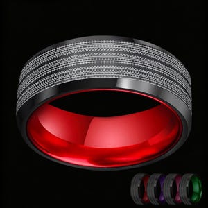 May include: A black band ring featuring a wide outer surface with intricate, repeating white geometric line patterns. The interior of the ring is a vibrant, solid red color. Four smaller versions of the ring are visible in the bottom corner.