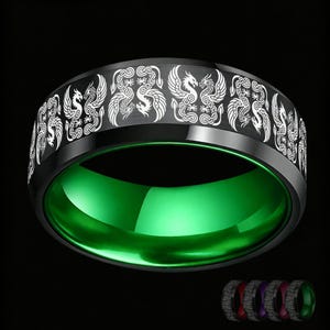 Puede incluir: Un anillo de banda negra con un patrón de dragón grabado en blanco que se repite alrededor de la superficie exterior. El interior del anillo tiene un acabado verde pulido y vibrante. El diseño incluye múltiples motivos de dragones en serie.
