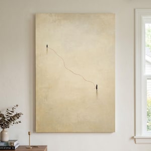 May include: A rectangular wall art print featuring a minimalist beige background with two small, dark figures standing at a distance from each other, connected by a single, thin, wavy red line that stretches across the center of the canvas.