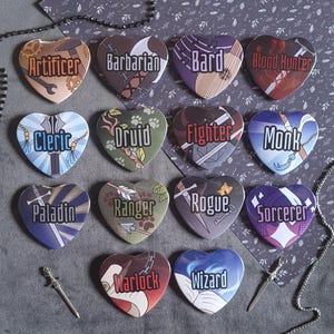 May include: A collection of fourteen heart-shaped pins featuring Dungeons and Dragons character classes including Artificer, Barbarian, Bard, Blood Hunter, Cleric, Druid, Fighter, Monk, Paladin, Ranger, Rogue, Sorcerer, Warlock, and Wizard.
