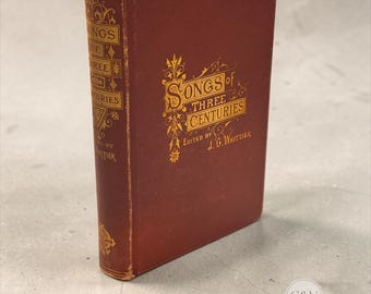 以下が含まれることがあります： J.G.ウィティア編集の「Songs of Three Centuries」というタイトルのヴィンテージハードカバー本。深みのある赤色の布製カバーで、表紙と背表紙には金色のエンボス文字と装飾的なフィリグリーのディテールが施されています。