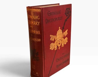 以下が含まれることがあります： Catholic Dictionary and Encyclopedia of Religious Informationというタイトルの赤いハードカバーの本。表紙には金色のエンボス加工された文字と、教皇の三重冠と鍵の中央エンブレムが施されています。背表紙にも金色の文字が記されています。