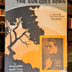 Könnte beinhalten: Ein altes Notenblatt mit dem Titel Down Where The Sun Goes Down, das eine schwarze Baumsilhouette vor einem gelben Sonnenuntergang zeigt. Es enthält ein Porträt von Verne Buck, Nennungen von Isham Jones und den Text Fox Trot song.