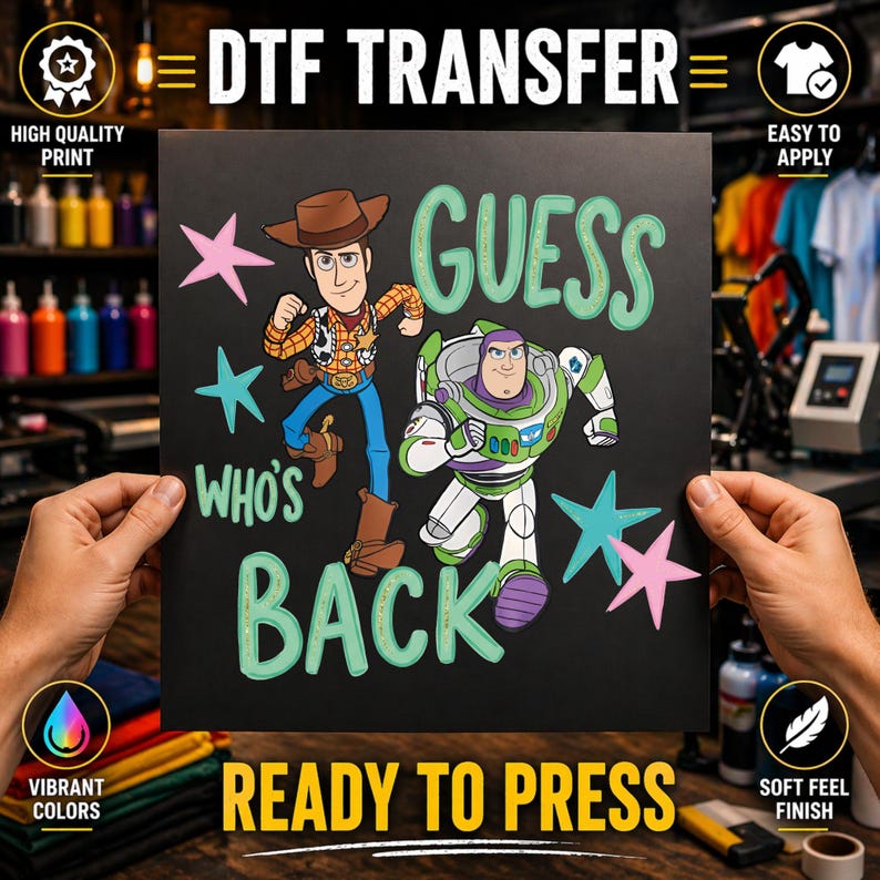 Op de afbeelding: Een zwart DTF-transfervel met Woody en Buzz Lightyear uit Toy Story. De tekst luidt GUESS WHO'S BACK in lichtgroene letters. Het ontwerp bevat roze en blauwgroene sterren verspreid rond de personages op een donkere achtergrond.
