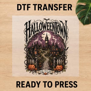 May include: A DTF transfer sheet featuring a gothic Halloweentown illustration with a central clock tower, winding stone path, bare trees, and orange jack-o'-lanterns. The text reads HALLOWEENTOWN and WELCOME, FOOLISH MORTALS. The design is ready to press.