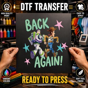 Op de afbeelding: Een zwart DTF-transfervel met de tekst BACK AGAIN! in lichtgroen, met illustraties van Buzz Lightyear en Woody uit Toy Story die rennen. Het ontwerp is versierd met roze en lichtblauwe sterren, klaar voor toepassing met hitte.