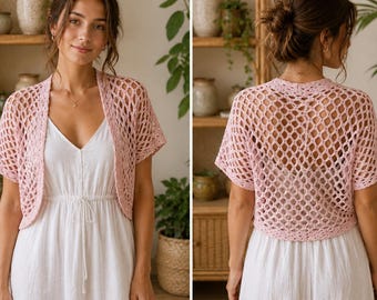May include: A light pink crochet shrug featuring an open diamond-shaped mesh pattern, short sleeves, and an open front design. The garment is worn over a simple white dress, showcasing both the front and back views of the knit construction.