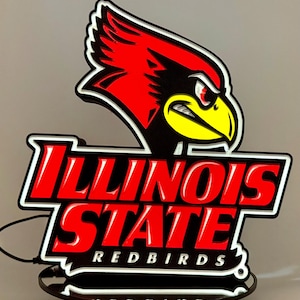 Op de afbeelding: Een LED-wandbord met het logo van de Illinois State Redbirds. Het ontwerp bevat een rode kardinaalkop met een gele snavel en zwarte accenten, geplaatst boven de rode tekst Illinois State en de witte tekst Redbirds.