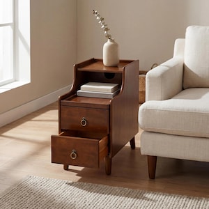 May include: A dark brown wooden end table featuring an open top shelf, a middle shelf holding two stacked books, and two drawers with circular brass-toned ring pulls. The bottom drawer is pulled open, revealing the interior wooden construction.