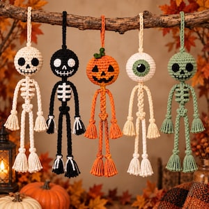 以下が含まれることがあります： ハロウィーンのキャラクターをモチーフにした5つの吊り下げ式かぎ針編みオーナメント。白い骸骨、黒い骸骨、オレンジ色のカボチャ、白い目玉、緑色の骸骨が並んでいます。各フィギュアには吊り下げ用のループが付いており、手足の先はタッセル状になっています。