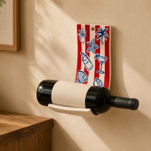 May include: A wall-mounted ceramic wine rack featuring a vertical rectangular backplate with red and white vertical stripes. The backplate is decorated with blue hand-painted illustrations of a lemon, palm tree, bottle, cocktail glass, and shell.
