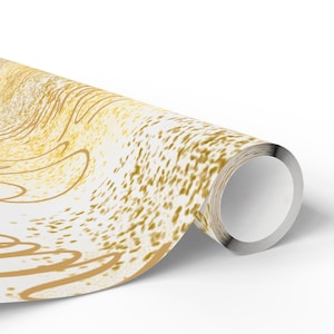 Op de afbeelding: Een rol inpakpapier met een witte achtergrond en een abstract patroon in goudkleur. Het ontwerp bestaat uit verspreide gouden spikkels en vloeiende, gebogen lijnen die een dynamisch, getextureerd uiterlijk creëren op het oppervlak van het papier.