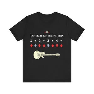 Könnte beinhalten: Ein schwarzes Kurzarm-T-Shirt mit dem weißen Text UNIVERSAL RHYTHM PATTERN über einer Abfolge von Zahlen und Pluszeichen, gefolgt von einer Reihe roter und blauer Pfeile und einer Grafik einer cremefarbenen E-Gitarre am unteren Rand.