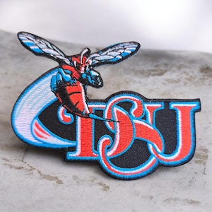 May include: An embroidered patch featuring a stylized hornet in red, blue, and white, positioned above the bold, red, and blue outlined letters "TSU" set against a black background, with a sweeping blue motion trail behind the hornet.