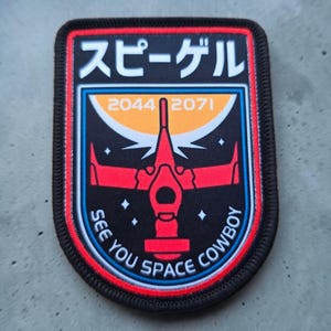 May include: A rectangular embroidered patch with rounded corners featuring a black background, a red spaceship graphic, and an orange crescent shape. The text reads "2044 2071", "SEE YOU SPACE COWBOY", and Japanese characters at the top.