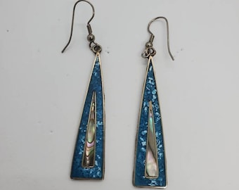 May include: A pair of silver-tone earrings with a triangular design. The earrings feature a turquoise-colored inlay with iridescent abalone shell accents. The earrings have a hook closure.