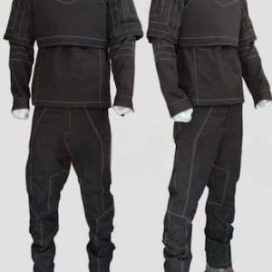 May include: A black long-sleeved shirt and trousers set featuring a high collar, a structured chest plate, and visible white topstitching throughout the garment. The outfit includes matching trousers with reinforced knee panels and brown leather boots.