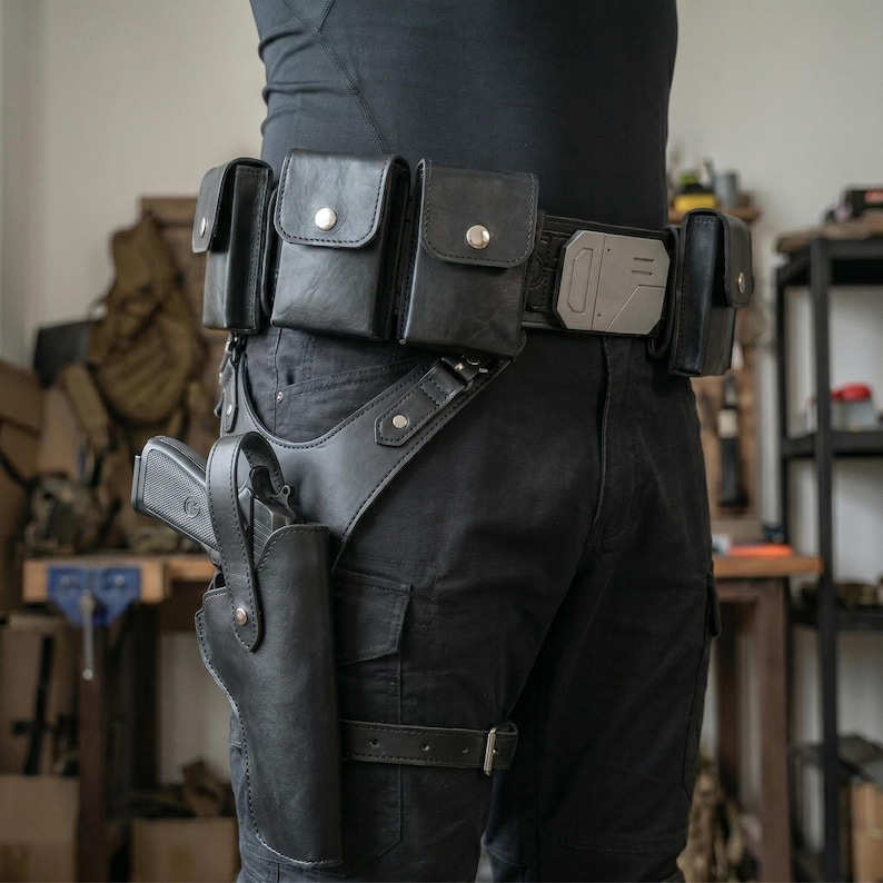 May include: A black utility belt featuring multiple rectangular pouches with silver-toned snap closures, a central metallic buckle plate, and a drop-leg holster containing a black handgun, all secured with adjustable leather straps and metal hardware.
