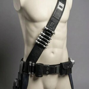 May include: A black leather utility belt and shoulder strap set featuring silver-toned cylindrical canisters attached to the strap and belt. The gear includes multiple pouches, a holster, and a metallic buckle, all displayed on a neutral mannequin torso.