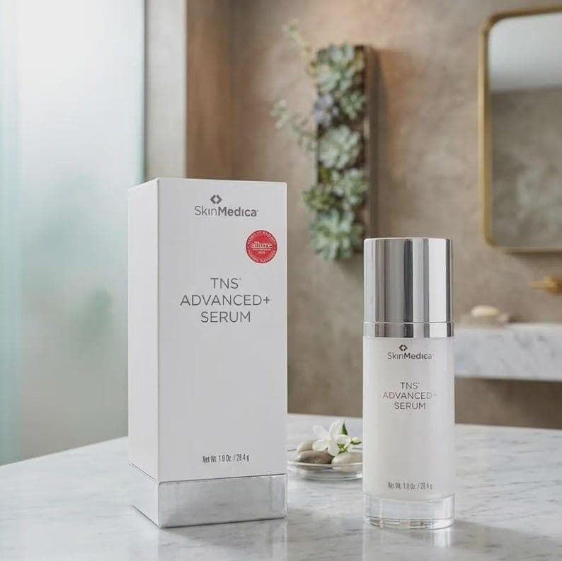 May include: A white SkinMedica TNS ADVANCED+ SERUM box and a matching cylindrical bottle with a silver cap. The packaging features black text, a red circular award seal, and states a net weight of 1.0 oz / 28.4 g on the front of both items.