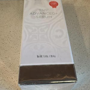 May include: A white rectangular SkinMedica TNS Advanced+ Serum box with a metallic silver base. The front features the text SkinMedica, TNS Advanced+ Serum, and a red Allure award seal. The net weight is printed as 1.0 oz. / 28.4 g on the front.