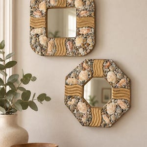 May include: Two wall mirrors with frames decorated in natural seashells, small grey pebbles, and textured tan wavy wooden accents. One mirror is square with rounded corners, and the other is octagonal, both featuring reflective glass centers.