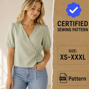 Può includere: Una camicetta a portafoglio verde salvia con maniche corte a sbuffo e scollo a V, indossata con jeans blu. L'immagine include il testo CERTIFIED SEWING PATTERN, SIZE: XS-XXXL e PDF Pattern, con un'icona di spunta blu su sfondo marrone.