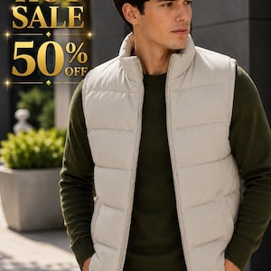 Puede incluir: Un chaleco acolchado de color beige sobre un suéter de manga larga verde oliva y pantalones claros. La imagen incluye texto dorado que dice HOT SALE 50% OFF. El chaleco tiene cuello alto, cierre de cremallera frontal y bolsillos laterales.