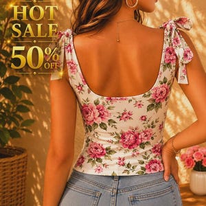 Puede incluir: Una blusa blanca sin mangas con estampado floral rosa, escote redondo y tirantes que se atan en lazos. El texto HOT SALE 50% OFF es visible a la izquierda. La blusa se combina con unos pantalones vaqueros de color azul claro.