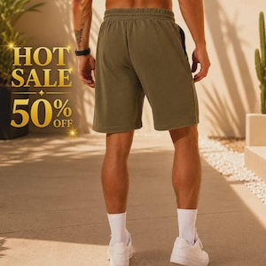 Puede incluir: Pantalones cortos deportivos de color verde oliva con cintura elástica y cordón, combinados con calcetines blancos y zapatillas blancas. El texto HOT SALE 50% OFF aparece en letras doradas en el lado izquierdo de la imagen.