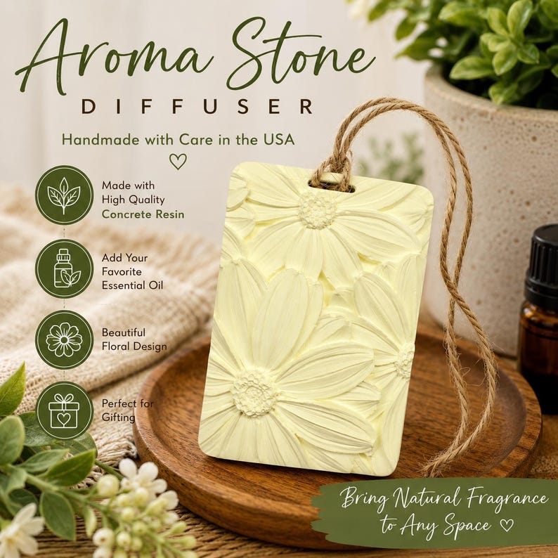 May include: A rectangular pale yellow concrete resin aroma stone diffuser featuring a raised floral daisy pattern. The diffuser includes a brown twine hanging loop and is printed with the text Aroma Stone Diffuser, Handmade with Care in the USA.