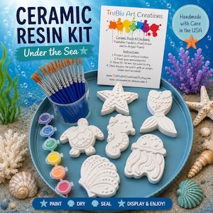 May include: A ceramic resin kit featuring five white paintable sea-themed figures, a clear cup filled with paintbrushes, and six small pots of acrylic paint on a blue tray. A white instruction card is included with the text TruBlu Art Creations.