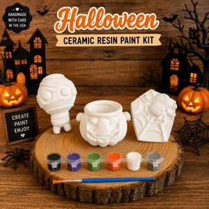 May include: A Halloween ceramic resin paint kit featuring three white unpainted figures: a mummy, a jack-o'-lantern cauldron, and a spider on a web. Includes six small paint pots in black, purple, green, orange, white, and gray, plus a paintbrush.