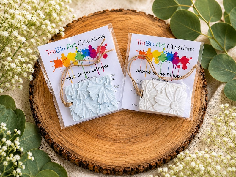May include: Two rectangular aroma stone diffusers in clear plastic packaging with twine hangers. One stone is light blue and the other is white, both featuring embossed floral patterns. The labels read TruBlu Art Creations Aroma Stone Diffuser.